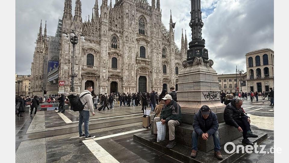 Trotz Rauchverbots sitzen zwei Männer mit Zigaretten in der Hand vor dem Mailänder Dom. Bild: Christoph Sator/dpa