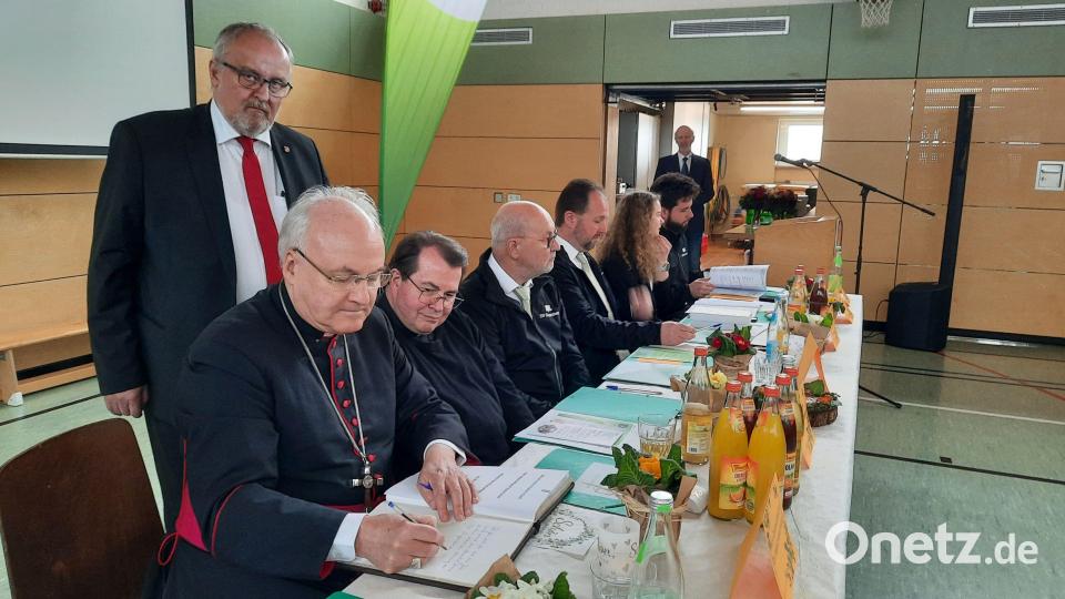 Bischof Rudolf Voderholzer trug sich im Beisein von Pfarrer Klaus Haußmann (rechts daneben) und Bürgermeister Anton Peter (stehend) ins Goldene Buch von Ammerthal ein. Bild: oe