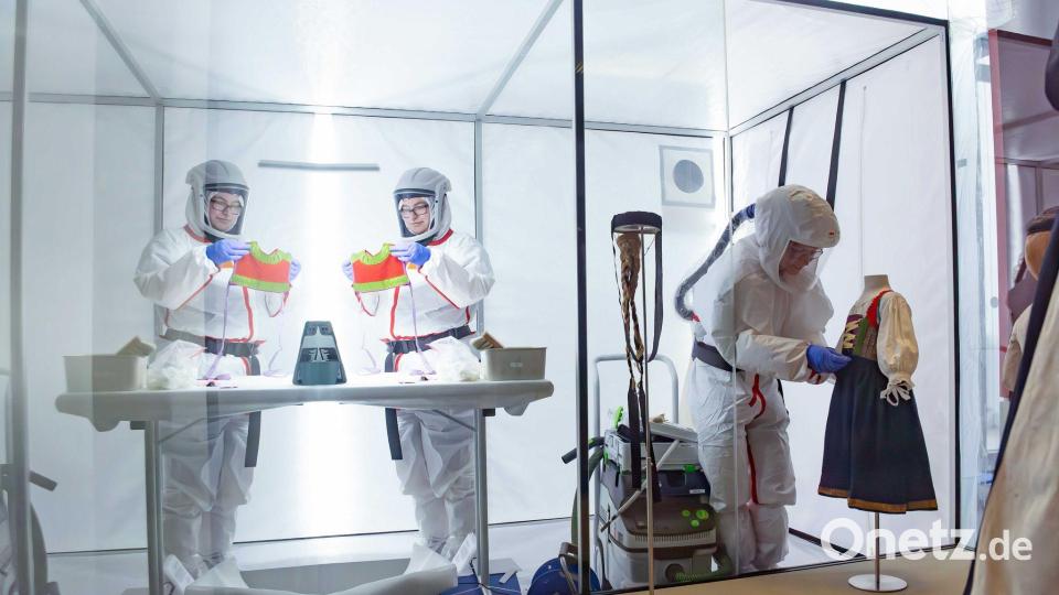 Die Trachten wurden in der Vergangenheit mit Insektengift behandelt. Deshalb müssen sich die Restauratorinnen beim Einpacken schützen. Bild: Daniel Löb/dpa