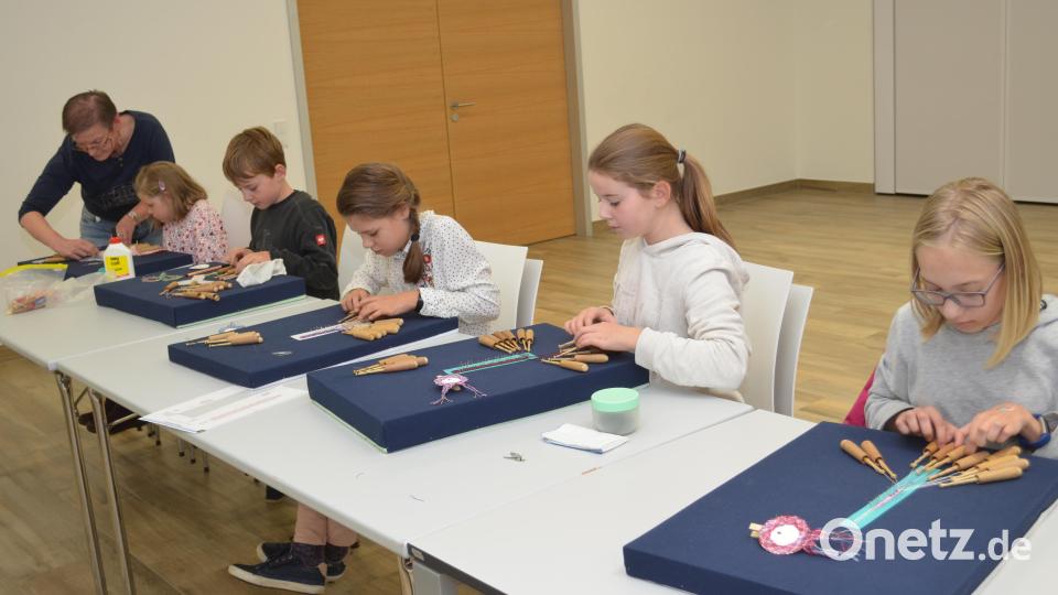 Sticker wie Fische oder Blüten und ein Freundschaftsbändchen klöppeln die Kinder unter Anleitung von Sabine Heibl. Bild: fz
