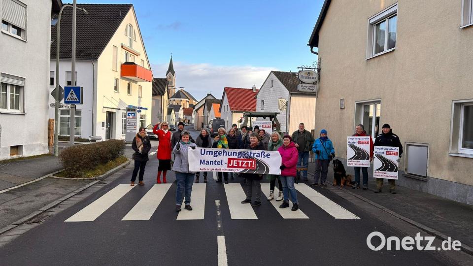 Anlieger der Hüttener Straße und Mitglieder der Bürgerinitiative „Umgehungsstraße Mantel – jetzt!“ bremsten den Verkehrsfluss am Zebrastreifen beim Gasthaus „Hauptmann“ und machten auf die Forderung nach einer Umgehungsstraße aufmerksam. Bild: knh