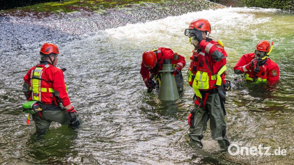 In Spezialanzügen, ausgerüstet mit Schnorchel und Taucherbrille, suchen die Polizeitaucher den Grund des Eisbahcs ab. Bild: Peter Kneffel/dpa