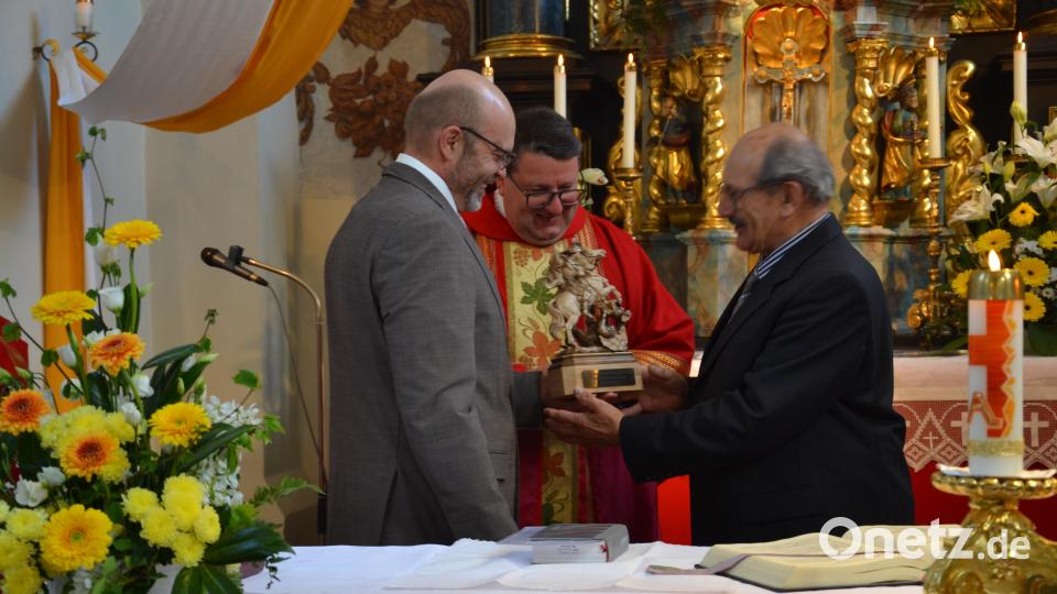Kirchenpfleger Eduard Ach (links) und Pfarrer Udo Klösel überreichen an den scheidenden Mesner Gerhard Uschold (rechts) zur Erinnerung eine geschnitzte Holzfigur des Kirchenpatrons von Etzgersrieth, dem Heiligen Georg. Bild: gi