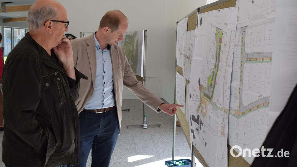 Wernbergs Bürgermeister Konrad Kiener zeigt den Besuchern die Detailplanung des neuen Baugebietes &quot;Am Köblitzbach&quot;. Bild: bnr