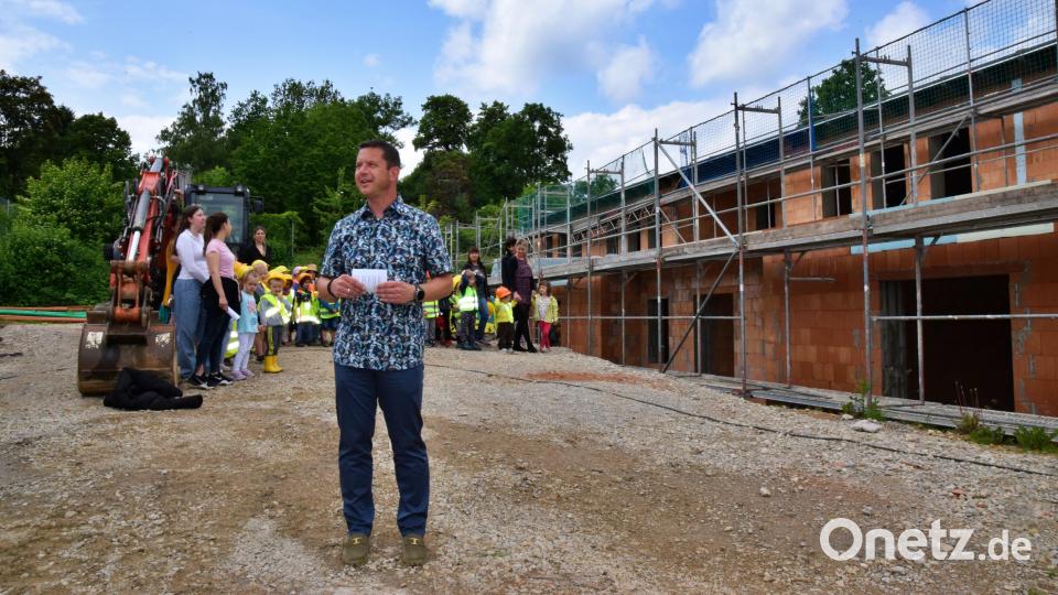 Bürgermeister Jörk Kaduk bei seiner Begrüßungsrede vor dem Rohbau. Die Kindergartenkindern (im Hintergrund) sangen zur Feier des Tages das Lied &quot;Wer will fleißige Handwerker sehen&quot;. Bild: hdk