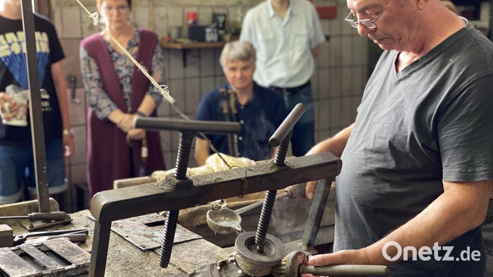 In der Zinngießerei zeigt &quot;Meister Hubert Schreiner&quot;, wie ein Krugdeckel gegossen wird. Bild: aub
