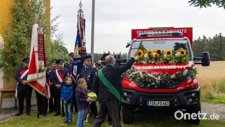 Diakon Martin Schraml segnete das neue Einsatzfahrzeug der Feuerwehr Siegritz – das Weihwasser kam dabei stilgerecht aus einem Feuerwehrhelm. Bild: Roland Wellenhoefer