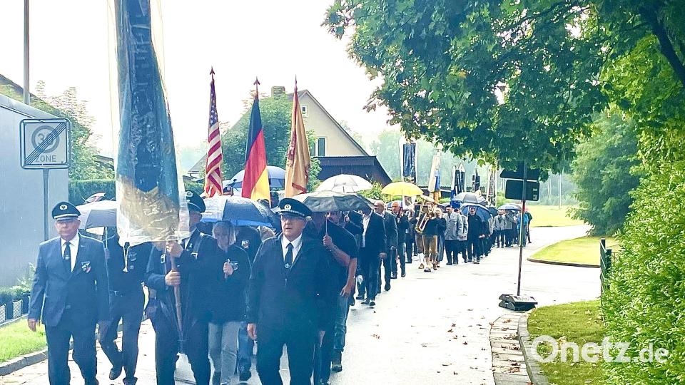 Der Kirchenzug machte sich bei strömenden Regen auf den Weg Richtung Kirche. Regenschirme halfen nur bedingt und viele Teilnehmer kamen durchnässt dort an. Bild: Gerhard Krones