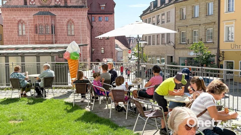 Vom vielen Regen der letzten Wochen ist der Rasen am Kirchenplateau saftig grün, die Sonne schien und es war angenehm war: Da schmeckt das Gratis-Eis – hier mit Blick auf das Rathaus – gleich umso besser. Bild: Petra Hartl