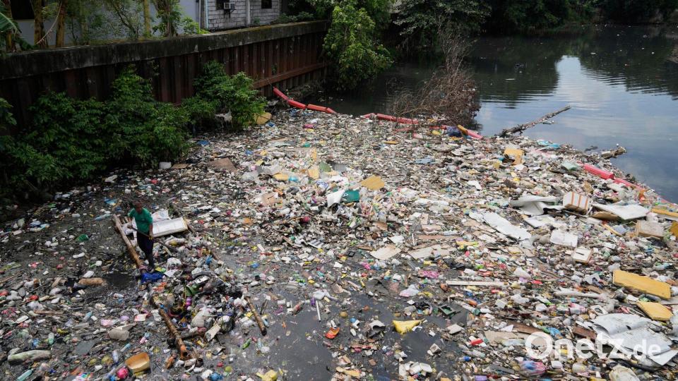 Kampf dem Müll: Ein Arbeiter sammelt Plastikmüll und andere Abfälle am San Juan-Fluss auf den Philippinen ein. Bild: Aaron Favila/AP/dpa