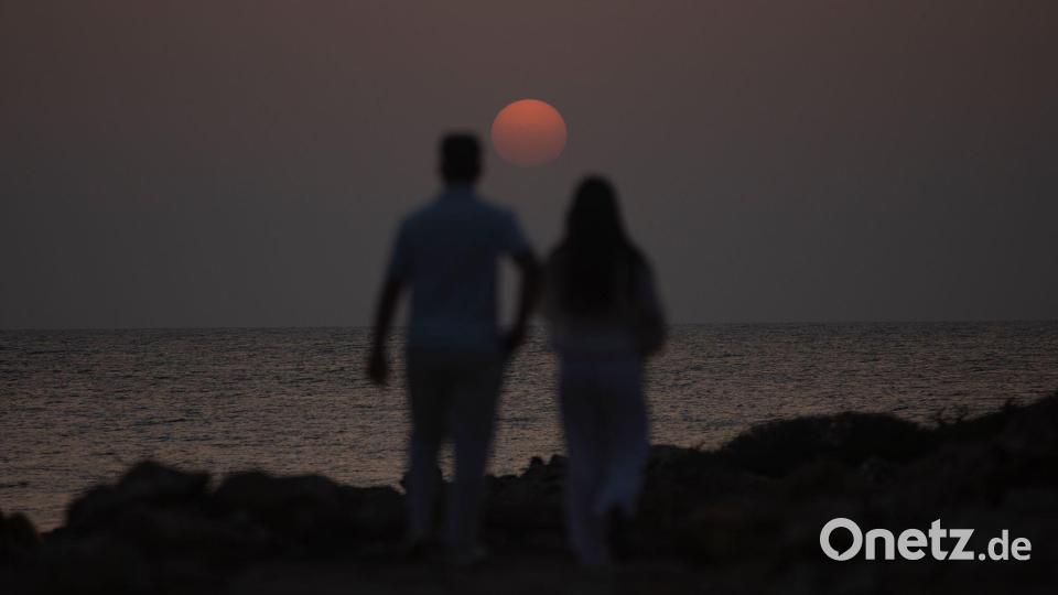 Ein Mann und eine Frau spazieren in der Nähe des Strandes Es Cargol in Santanyi auf Mallorca während des Sonnenuntergangs. Bild: Clara Margais/dpa