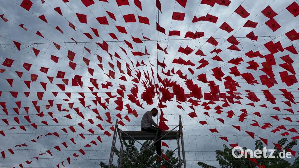 Ein Mann hängt Fahnenketten auf, um die Feierlichkeiten zum vietnamesischen Nationalfeiertag vorzubereiten. Bild: Hau Dinh/AP/dpa