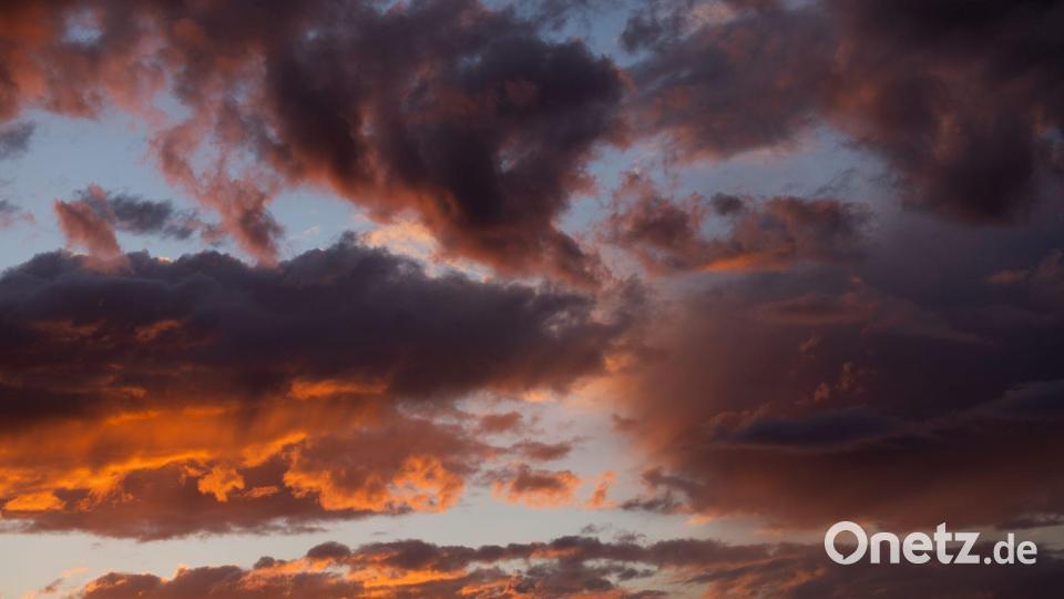 Die untergehende Sonne lässt die Wolken über Köln rötlich schimmern. Bild: Rolf Vennenbernd/dpa