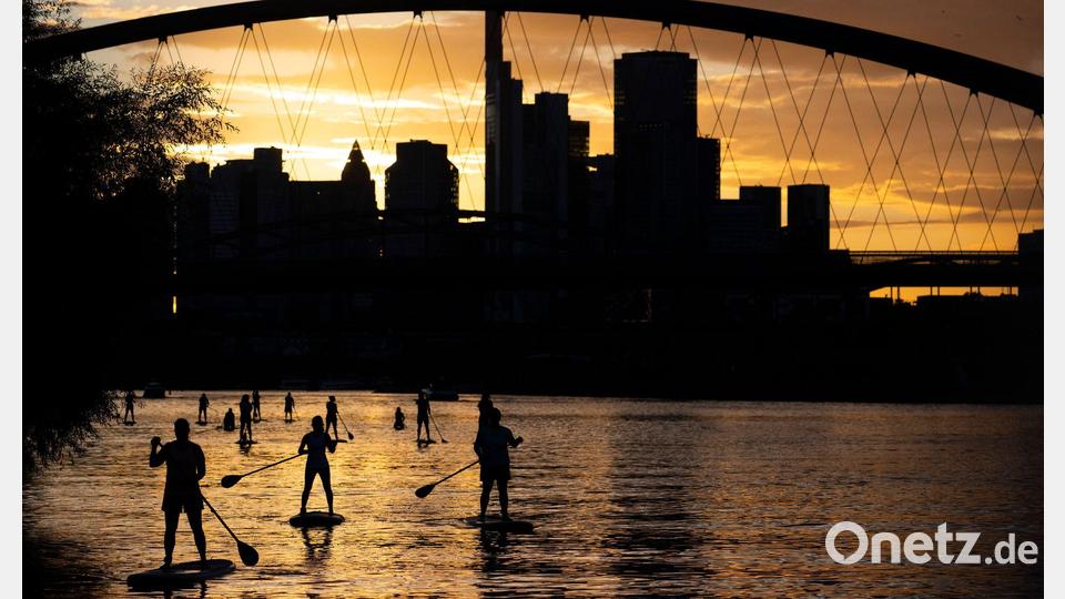 Bei Sicht auf die Skyline im letzten Licht des Tages fahren Stand-Up-Paddler in Nähe der Frankfurter Osthafenbrücke über den Main. Bild: Boris Roessler/dpa