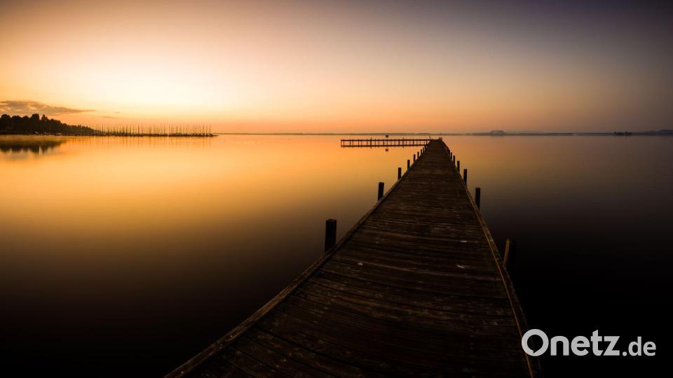 Der Himmel über einem Steg am Steinhuder Meer in der Region Hannover ist bei Sonnenaufgang orange. Bild: Moritz Frankenberg/dpa