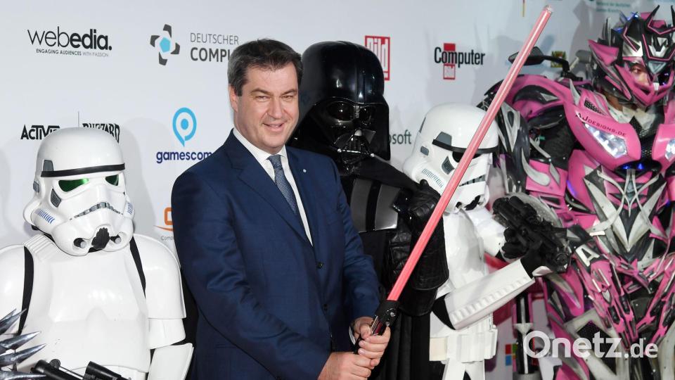 Markus Söder hält ein Laserschwert. Bild: Tobias Hase/dpa