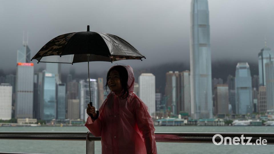 Ein Mädchen hält einen Regenschirm in Tsim Sha Tusi vor dem Victoria Harbor und der Skyline von Hongkong während des Taifuns „Tapah“. Bild: Vernon Yuen/Nexpher via ZUMA Press Wire/dpa