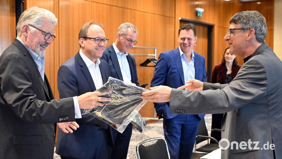 Zum Beginn der Tarifverhandlungen in der Stahlindustrie überreicht der Verhandlungsführer der IG Metall, Knut Giesler, zwei T-Shirts an den Verhandlungsführer der Arbeitgeber, Reiner Blaschek (2.v.l), sowie den Geschäftsführer des Arbeitgeberverbandes Stahl, Gerhard Erdmann (l). Bild: Federico Gambarini/dpa
