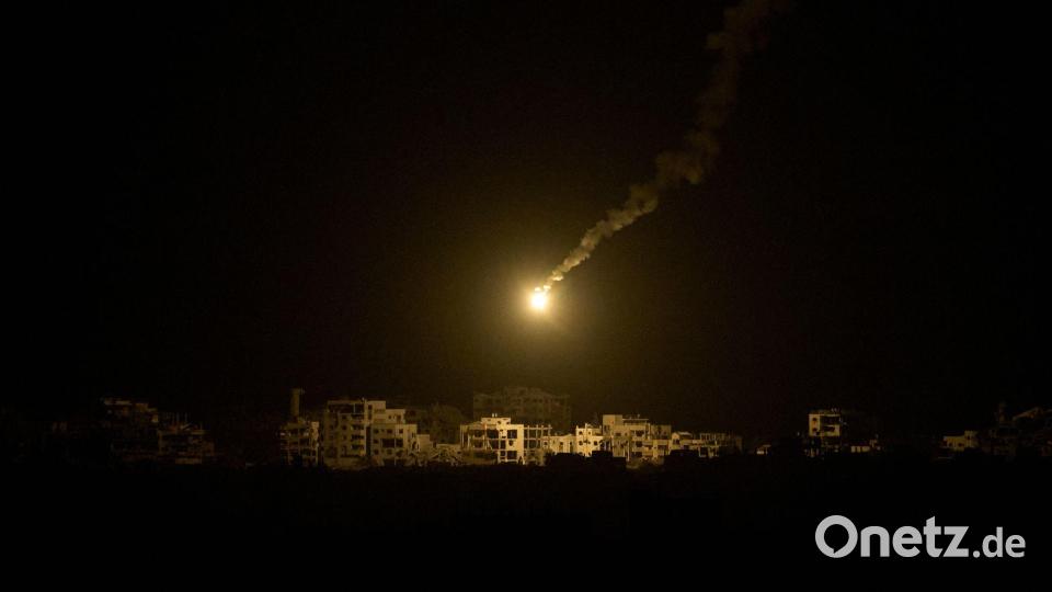 Eine Leuchtrakete der israelischen Armee fliegt über Gebäuden, die während der israelischen Boden- und Luftoperationen im nördlichen Gazastreifen zerstört wurden. Bild: Leo Correa/AP/dpa