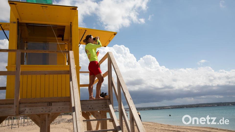 Ein Rettungsschwimmer benutzt ein Fernglas, während er am Strand von Palma auf Mallorca patrouilliert. Bild: Clara Margais/dpa