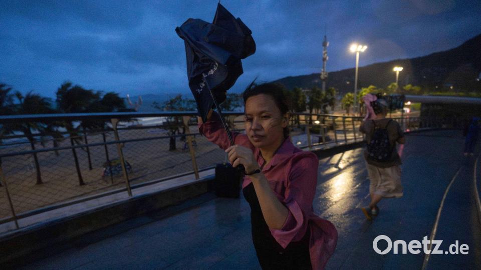 Eine Frau versucht, nach dem Super-Taifun Ragasa in Shenzhen in der südchinesischen Provinz Guangdong einen Regenschirm im Wind zu öffnen. Bild: Ng Han Guan/AP/dpa