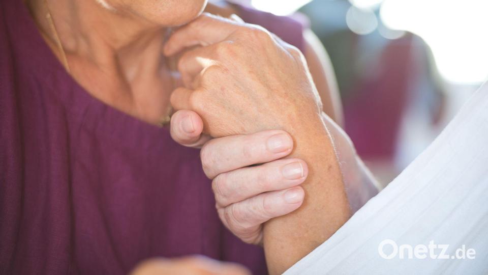 Eine Frau hält die Hand ihres an Demenz erkrankten Mannes. Bild: Daniel Naupold/dpa