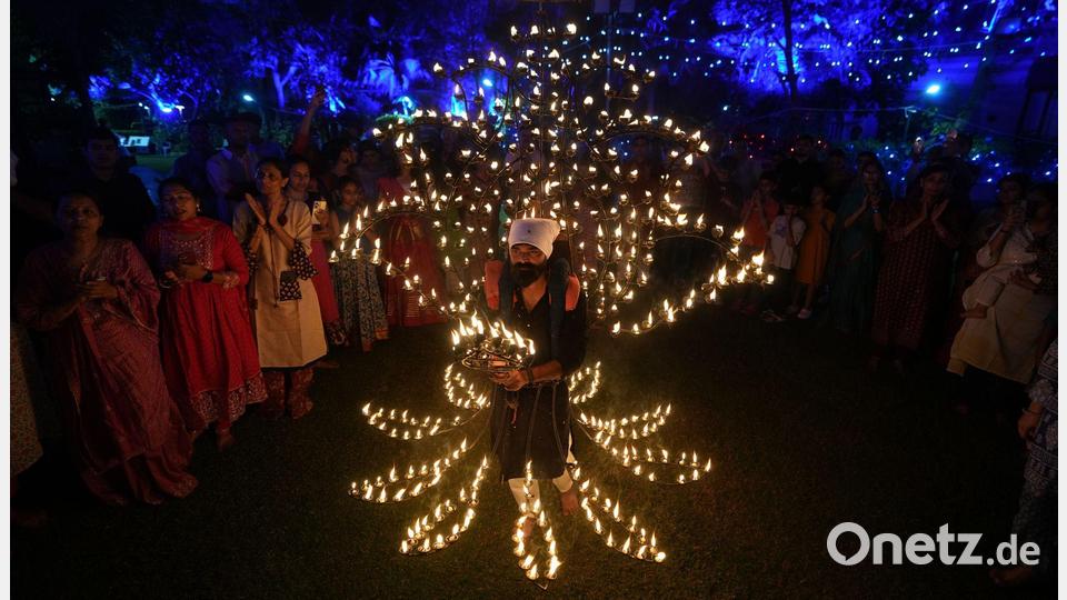 Ein Mann hält in einem mit Öllampen geschmückten Kostüm in der fünften Nacht von Navratri, dem Fest der neun Nächte, das Aarti-Ritual ab. Bild: Ajit Solanki/AP/dpa