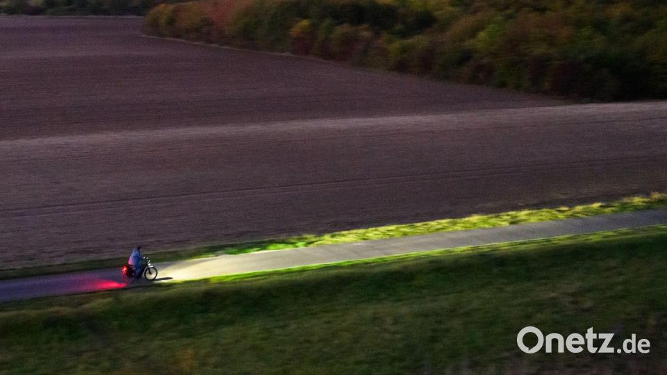 Ein Fahrradfahrer fährt am frühen Morgen mit Licht über einen Feldweg bei Hannover. Bild: Julian Stratenschulte/dpa