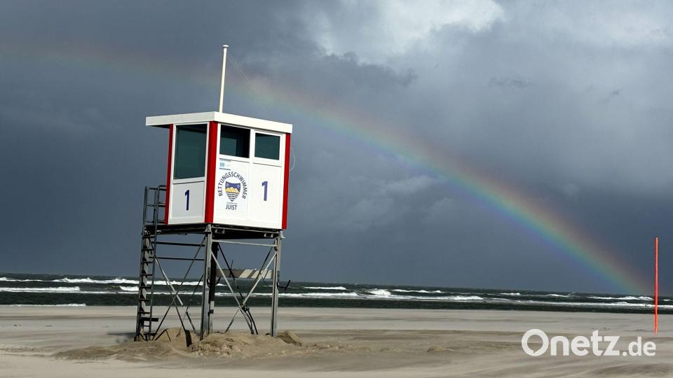 Ein Regenbogen steht an einem Himmel voll dunkler Wolken über der Nordsee und über der Insel Juist. Bild: Federico Gambarini/dpa