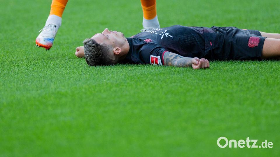 Bayer Leverkusens Kapitän Alejandro Grimaldo liegt nach einem Zusammenprall mit dem eigenen Mann benommen auf dem Boden. Bild: Rolf Vennenbernd/dpa