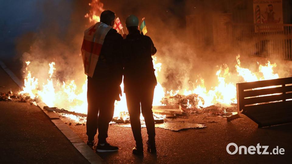 Demonstranten mit einer georgischen und einer ukrainischen Nationalflagge stehen im Stadtzentrum von Tiflis hinter einer brennenden Barrikade während einer Kundgebung der Opposition, bei der sie die Kommunalwahlen boykottieren und die Freilassung politischer Gegner fordern. Bild: Zurab Tsertsvadze/AP/dpa