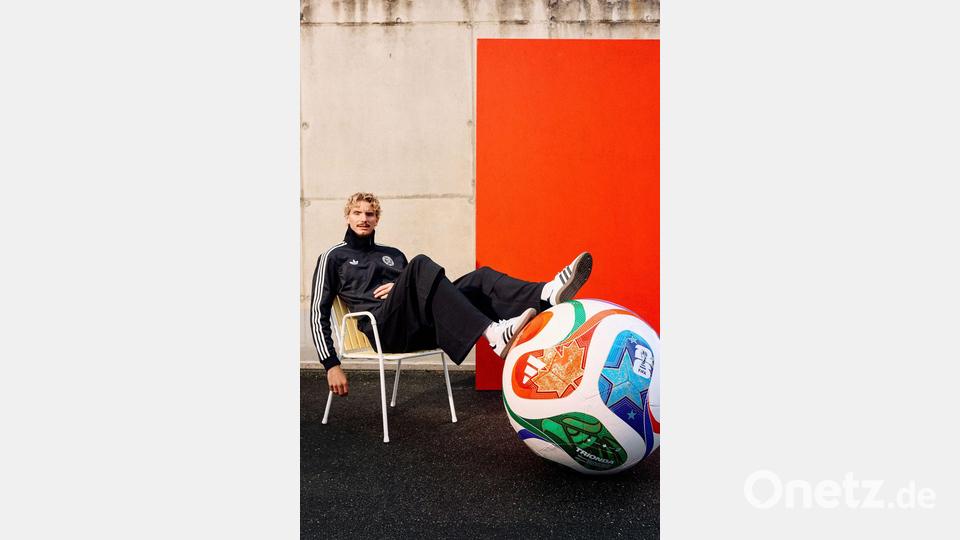 Woltemade posiert lässig mit dem übergroßen Modell des WM-Balls. Bild: ---/Adidas/dpa
