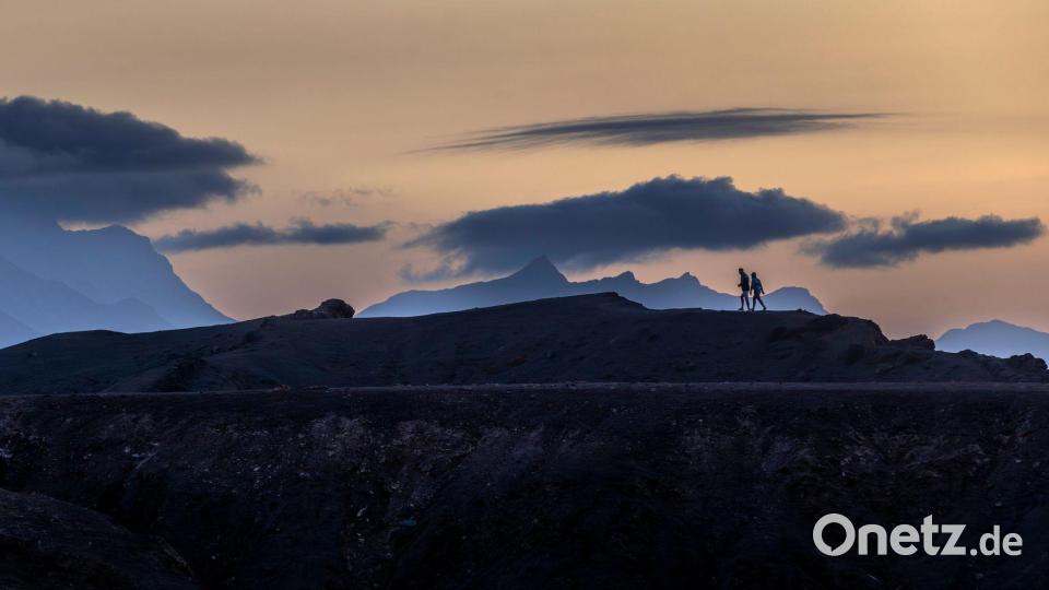 Panodrama: Menschen gehen auf der Insel Fuerteventura unter dramatisch wirkenden Wolkenformationen. Bild: Mindaugas Kulbis/AP/dpa
