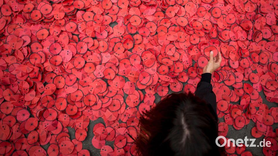 Eine Person hebt eine Papiermohnblume auf, die während einer Kundgebung gegen den Gaza-Krieg vor dem spanischen Außenministerium in Madrid auf dem Boden liegt. Bild: Luis Soto/SOPA Images via ZUMA Press Wire/dpa