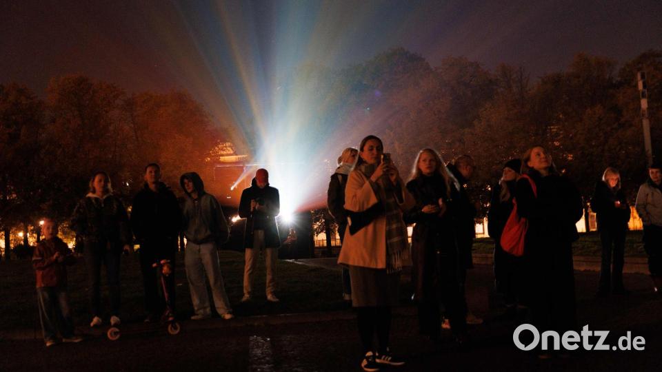 Menschen stehen vor einem Beamer, während der Berliner Dom bei der Generalprobe für das 21. Festival of Lights Berlin unter dem Motto „Let’s Shine Together“ angestrahlt wird. Bild: Carsten Koall/dpa