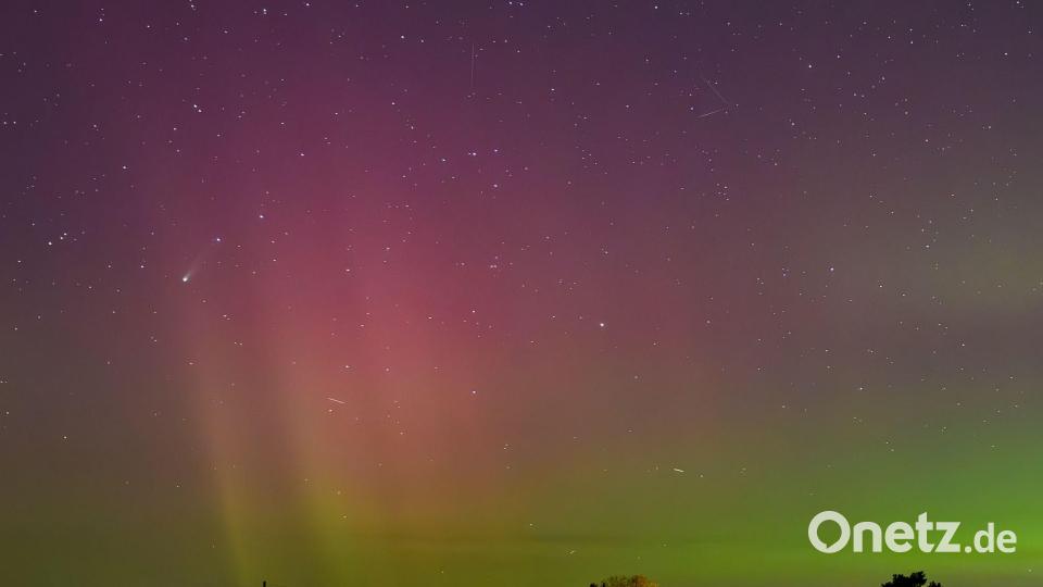 Polarlichter und der Komet Lemmon „C/2025 A6“ (Bildmitte links) leuchten am Nachthimmel über der Landschaft im östlichen Brandenburg. Bild: Patrick Pleul/dpa