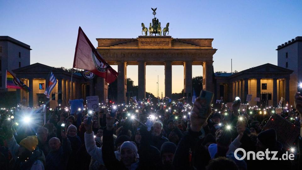 Demonstranten halten ihre Handys mit Taschenlampen vor dem Brandenburger Tor in die Luft. Die Demonstration unter dem Motto „Brandmauer hoch! Wir sind das Stadtbild“ bezieht sich auf eine Äußerung von Bundeskanzler Merz im Zusammenhang mit der Migrationspolitik. Bild: Annette Riedl/dpa