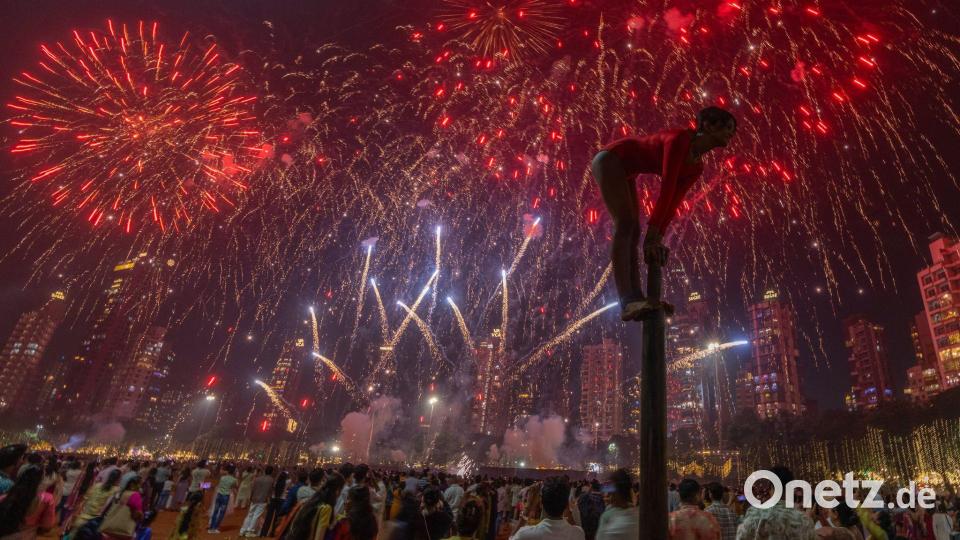 Ein Mädchen performt auf einer Mallakhamb-Stange, während Feuerwerkskörper den Himmel während des Diwali-Lichterfestes in Mumbai erhellen. Bild: Rafiq Maqbool/AP/dpa