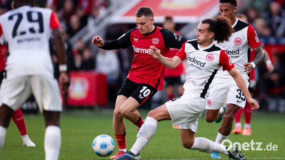 Für den Ex-Leverkusener Florian Wirtz (M) kommt es am Mittwoch zum Wiedersehen mit Eintracht Frankfurt um Arthur Theate (r). (Archivbild) Bild: Marius Becker/dpa