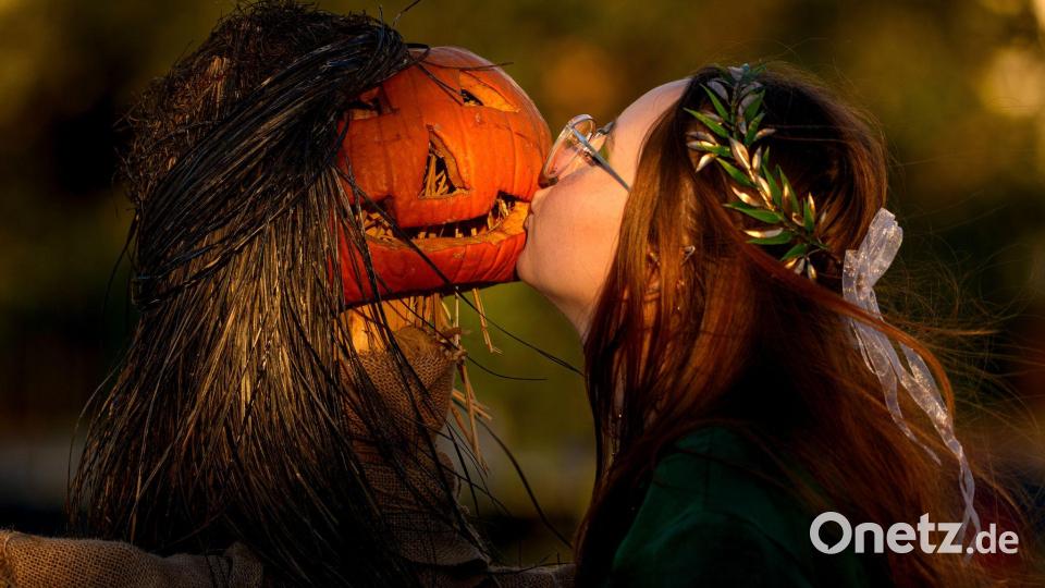 Ein Mädchen posiert für einen Freund und küsst einen Kürbis auf dem West Side Hallo Fest, dem größten Halloween-Festival des Landes, in Bukarest. Bild: Andreea Alexandru/AP/dpa