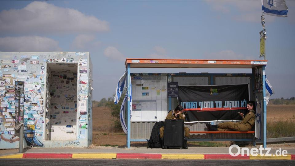 An einem Busbahnhof nahe der Grenze zum Gazastreifen warten israelische Soldatinnen auf den Transport. Bild: Ohad Zwigenberg/AP/dpa