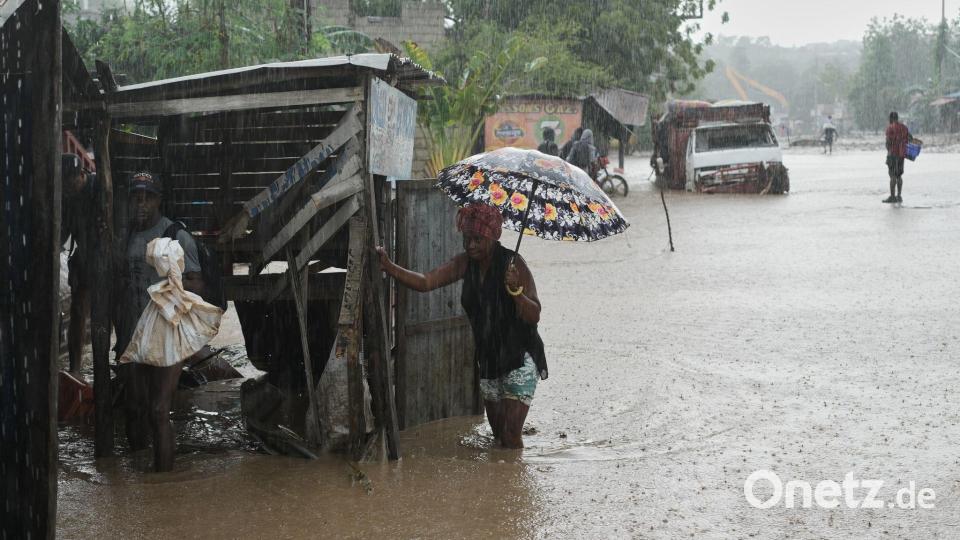 Anwohner waten durch eine überflutete Straße nach dem durchzug von Hurrikan Melissa in Petit-Goave. Bild: Odelyn Joseph/AP/dpa