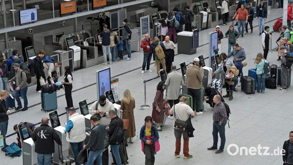 Reisegäste stehen an Check-In-Schaltern am Flughafen. Bild: Malin Wunderlich/dpa
