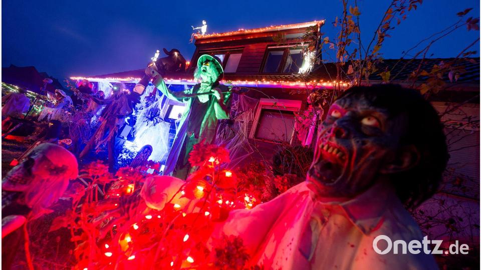 Gruselige Figuren stehen in Mettmann vor einem beleuchteten Halloween-Haus. Bild: Henning Kaiser/dpa