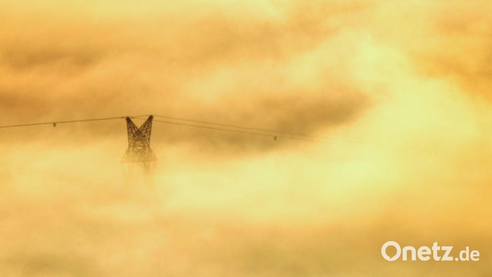 Sonnenaufgang in Riedlingen: Strommastspitze im goldenen Nebel Bild: Thomas Warnack/dpa