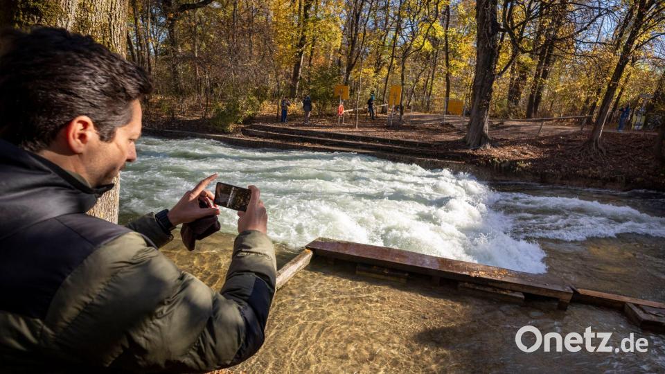 Freizeitsurfer Alexander Neumann fotografiert die - zurzeit nicht funktionstüchtige - Eisbachwelle im Englischen Garten. Bild: Peter Kneffel/dpa