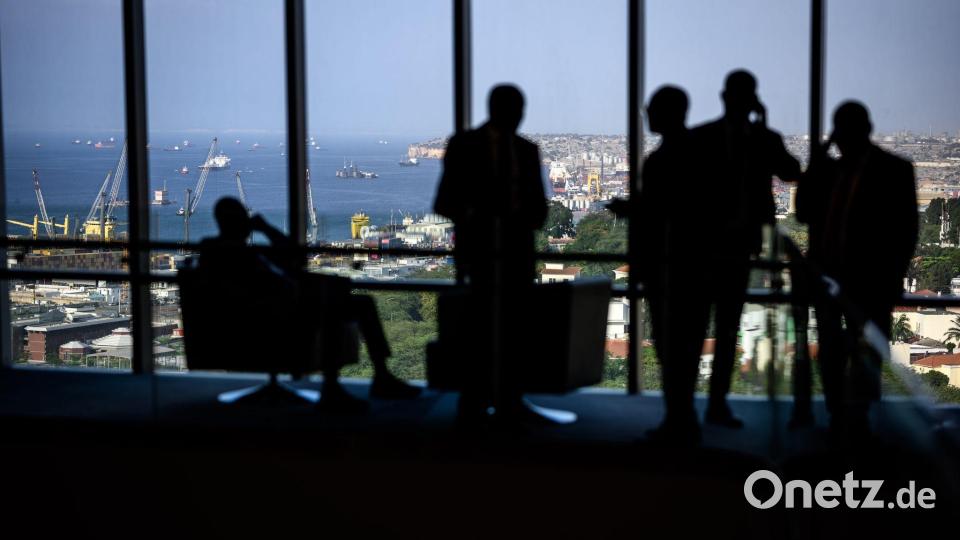 Hotelgäste stehen zum Teil telefonierend vor einem Panoramafenster in einem Luxushotel in Luanda. Bild: Bernd von Jutrczenka/dpa