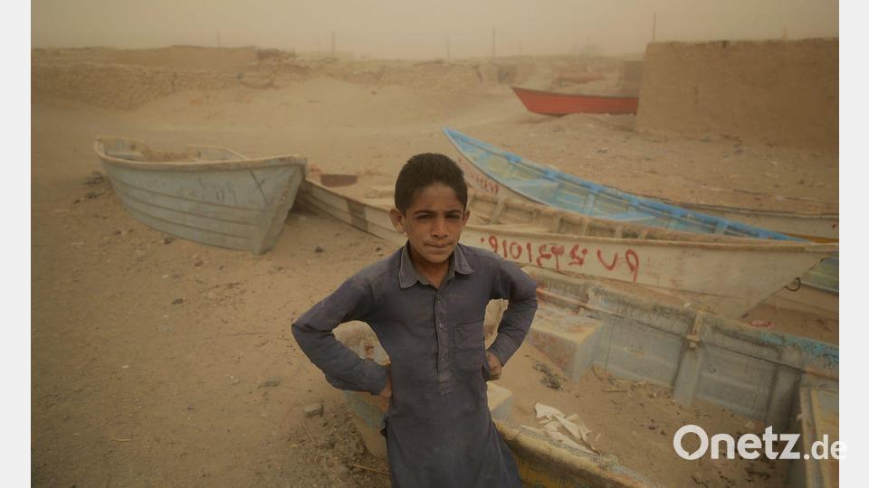 Ein Junge im Iran steht vor alten Booten, wo einst ein See war. Bild: Mohammad Dehdast/dpa