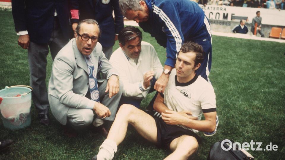Franz Beckenbauer wird im Halbfinalspiel der Fußball-WM 1970 in Mexiko Deutschland - Italien am 17.6.1970 vom deutschen Mannschaftsarzt Professor Schoberth (l.) und Masseur Erich Deuser (M.) eine Schulterbandage angelegt. Beckenbauer hatte sich zum Ende der regulären Spielzeit eine Verletzung an der Schulter zugezogen und mit dem Verband die zweimal 15 Minuten der Verlängerung durchgestanden. Deutschland verlor das Spiel im Aztekenstadion durch ein Tor von Rivera in der 111. Minute mit 3:4. Bild: Lothar Heidtmann/dpa