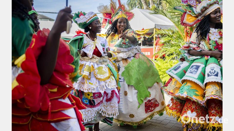 Bunt gekleidete Gäste feiern im Garten des Präsidentenpalastes von Suriname. Bild: Remko De Waal/ANP/dpa